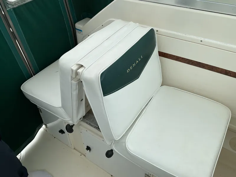 Slide: The Image of 1997 Pursuit 2460 Denali boat seating with white cushions and green accents. - 9