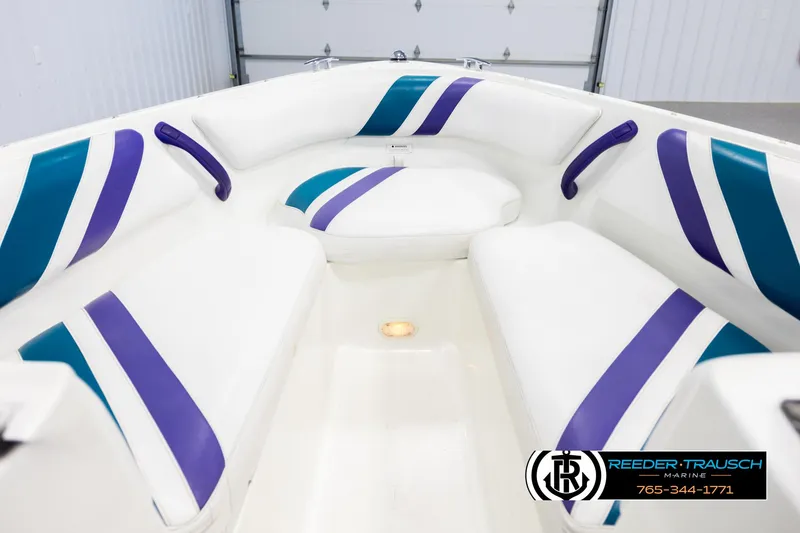 Slide: The Image of Interior of a 1997 Celebrity 190 boat with white, purple, and teal seating. - 15