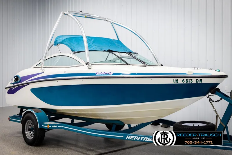 Slide: The Image of 1997 Celebrity 190 boat on trailer with blue and white design, displayed indoors. - 3