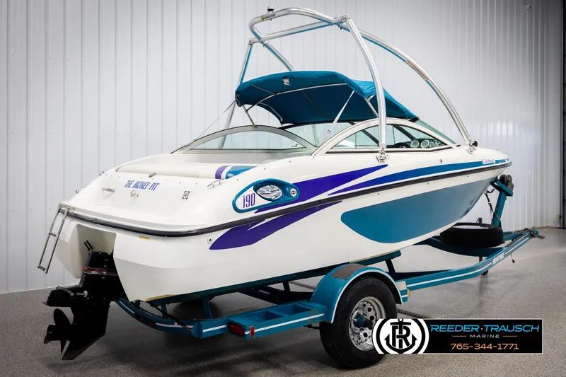 Slide: The Image of 1997 Celebrity 190 boat on trailer, white with blue accents, in indoor storage. - 6