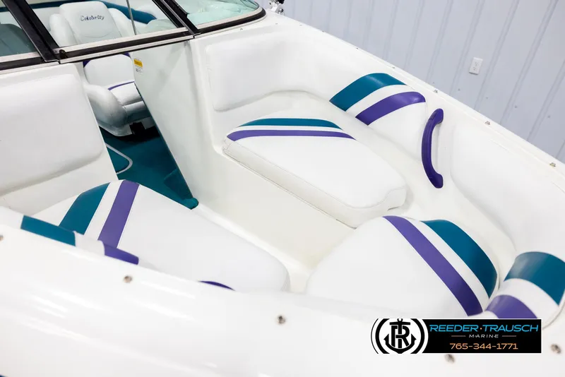 Slide: The Image of 1997 Celebrity 190 boat interior with white and purple seating, Reeder-Trausch Marine logo visible. - 9