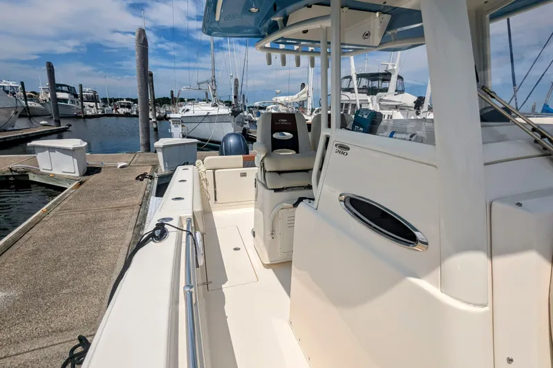 Slide: The Image of 2023 Cobia 280 Center Console boat docked at marina under clear sky. - 16
