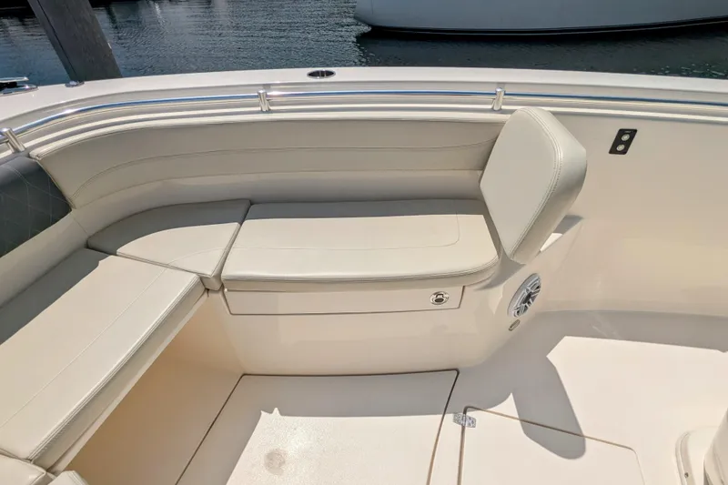 Slide: The Image of 2023 Cobia 280 Center Console boat seating area with cushioned benches and speaker. - 20