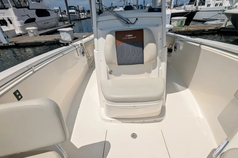 Slide: The Image of 2023 Cobia 280 Center Console boat interior at marina, featuring seating and clean design. - 21