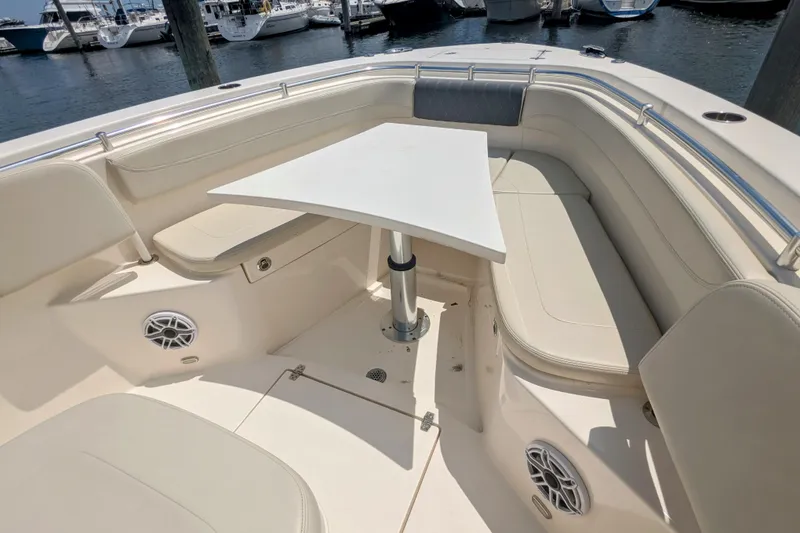 Slide: The Image of 2023 Cobia 280 Center Console boat interior with seating and table, docked at marina. - 22