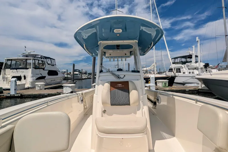 Slide: The Image of 2023 Cobia 280 Center Console boat docked at marina under blue sky. - 25
