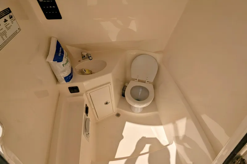 Slide: The Image of 2023 Cobia 280 Center Console boat bathroom with toilet and sink. - 27