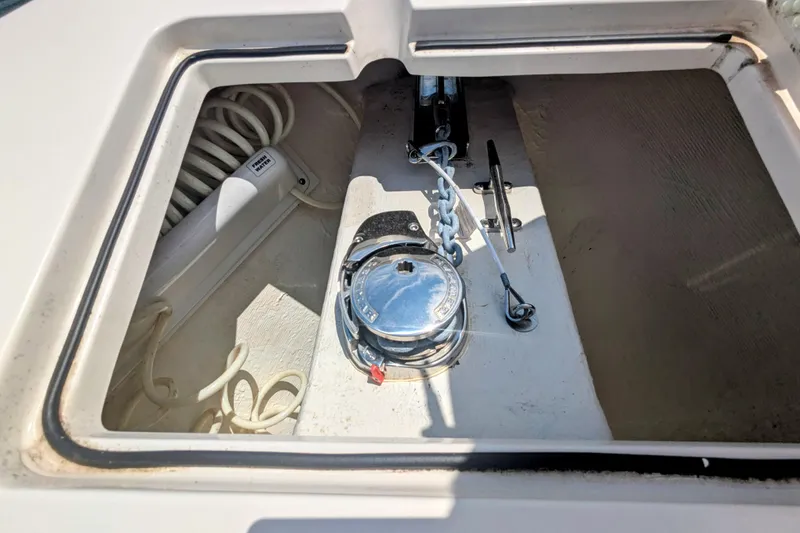 Slide: The Image of Anchor storage compartment on 2023 Cobia 280 Center Console boat, featuring coiled rope and metal fittings. - 28