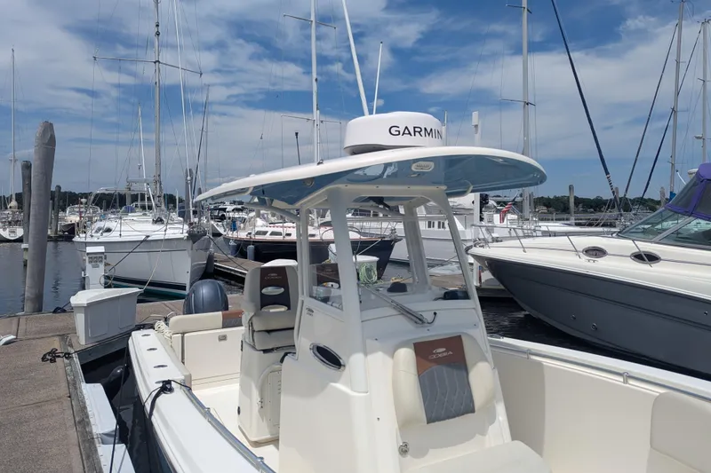 Slide: The Image of 2023 Cobia 280 Center Console boat docked at a marina with clear skies. - 7