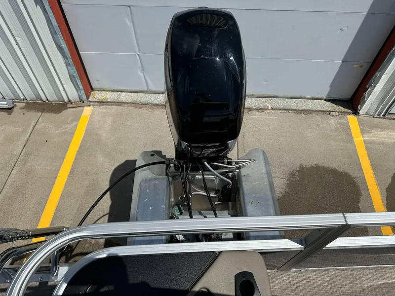 Slide: The Image of 2025 Sun Tracker Bass Buggy 18 DLX pontoon boat with outboard motor, parked on concrete. - 28