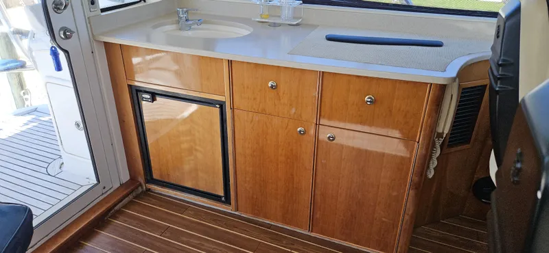 Slide: The Image of 2004 Riviera 58 Enclosed Flybridge interior with wooden cabinetry and compact sink area. - 26