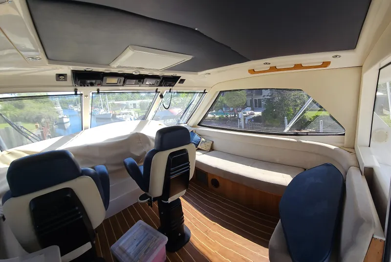 Slide: The Image of 2004 Riviera 58 Enclosed Flybridge interior with seating and helm, featuring panoramic windows. - 27