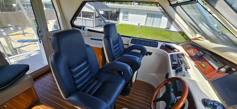Slide: The Image of 2004 Riviera 58 Enclosed Flybridge interior with leather seats and wooden dashboard. - 29