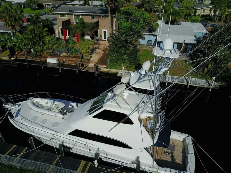 Slide: The Image of 2004 Riviera 58 Enclosed Flybridge yacht docked near waterfront homes. - 3
