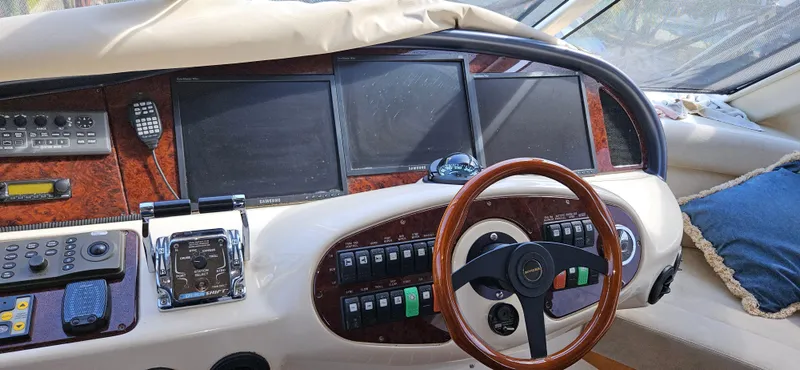 Slide: The Image of 2004 Riviera 58 Enclosed Flybridge helm with wood steering wheel and multiple control panels. - 31