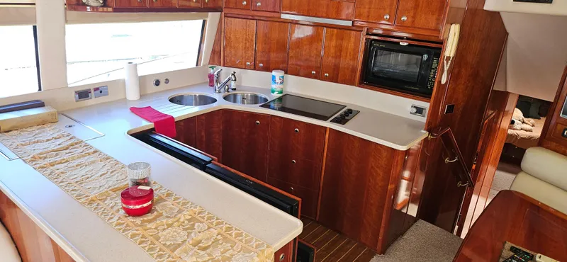 Slide: The Image of Luxurious kitchen interior of 2004 Riviera 58 Enclosed Flybridge yacht with wood cabinetry. - 43