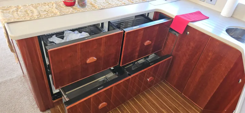 Slide: The Image of 2004 Riviera 58 Enclosed Flybridge kitchen with open wooden drawers and countertop. - 44