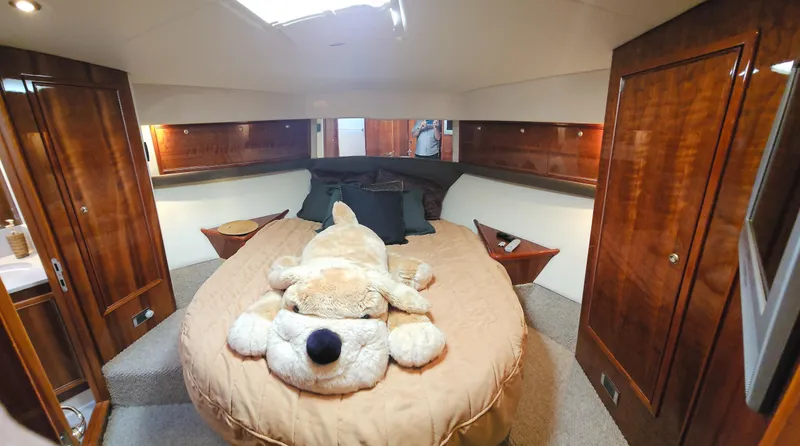 Slide: The Image of Luxurious 2004 Riviera 58 Enclosed Flybridge bedroom with plush decor and wooden cabinetry. - 49