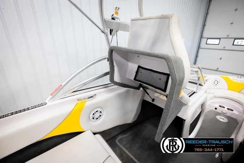 Slide: The Image of 2005 Correct Craft 226 Natique interior with open storage compartment, yellow accents, and marine speakers. - 23