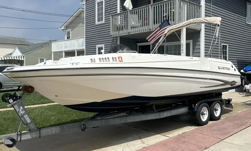 The Image of 2002 Glastron DX 215 boat on trailer, parked in residential area. - 0