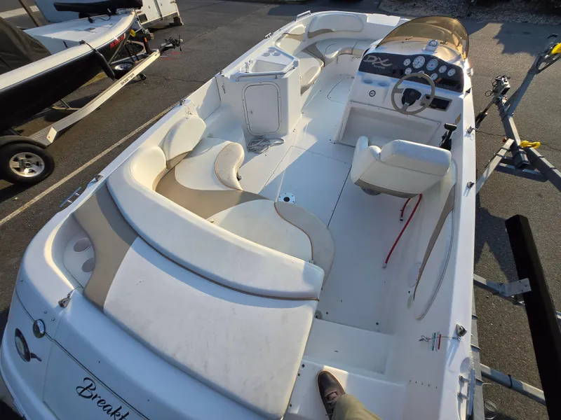 Slide: The Image of 2002 Glastron DX 215 boat interior with seating and steering wheel, parked on a trailer. - 2