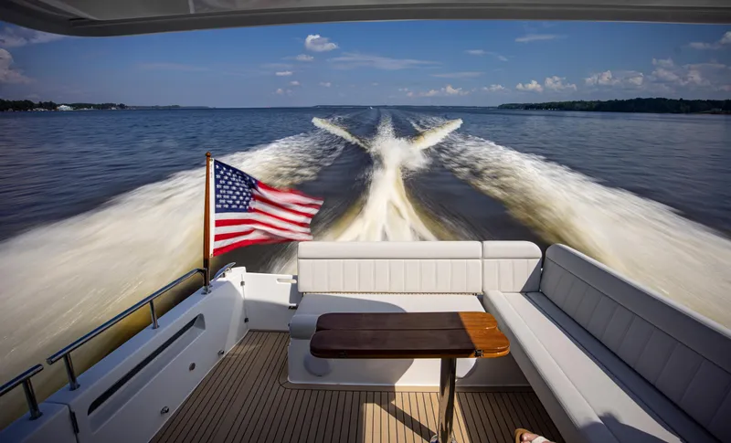 Slide: The Image of 2025 MJM 42 yacht cruising with American flag, leaving wake on open water. - 23