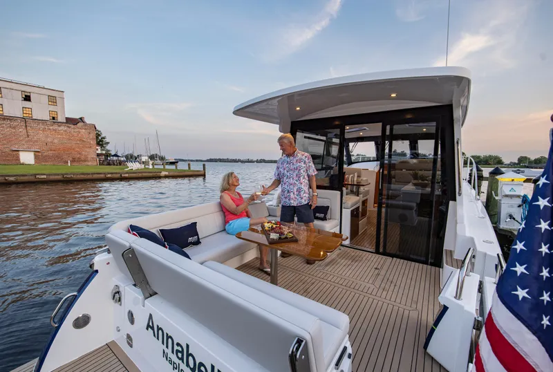 Slide: The Image of Couple enjoying drinks on a 2025 MJM 42 yacht, docked by a scenic waterfront. - 27