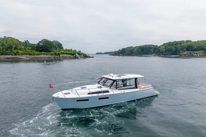 Slide: The Image of 2025 MJM 42 yacht cruising near lush, green shoreline. - 3