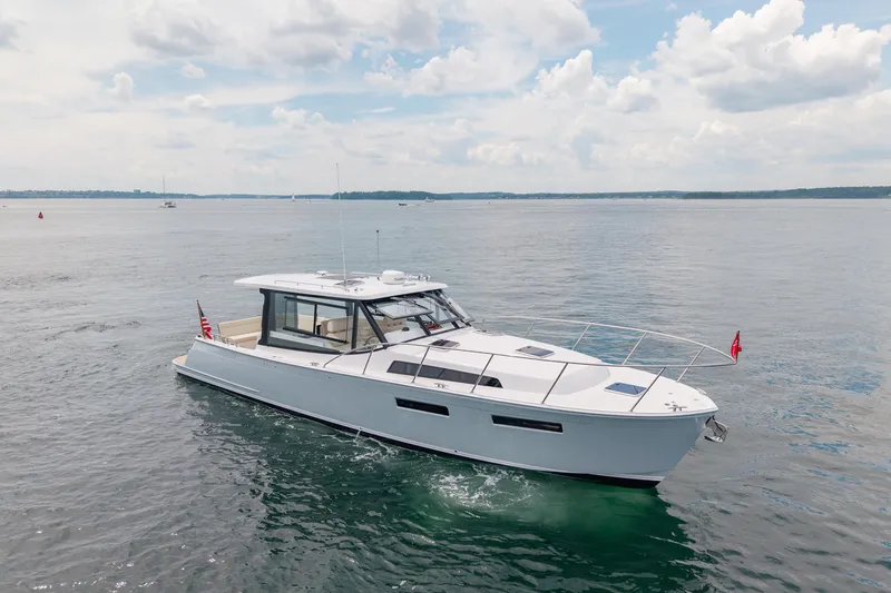 Slide: The Image of 2025 MJM 42 yacht cruising on calm waters under a partly cloudy sky. - 6