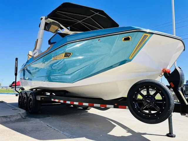 Slide: The Image of 2024 Nautique G25 Paragon boat on trailer, blue and white design, sunny day. - 4