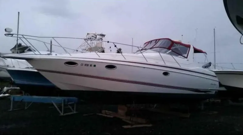 The Image of 1997 Chris-Craft 34 boat with red canopy, docked on land. - 0