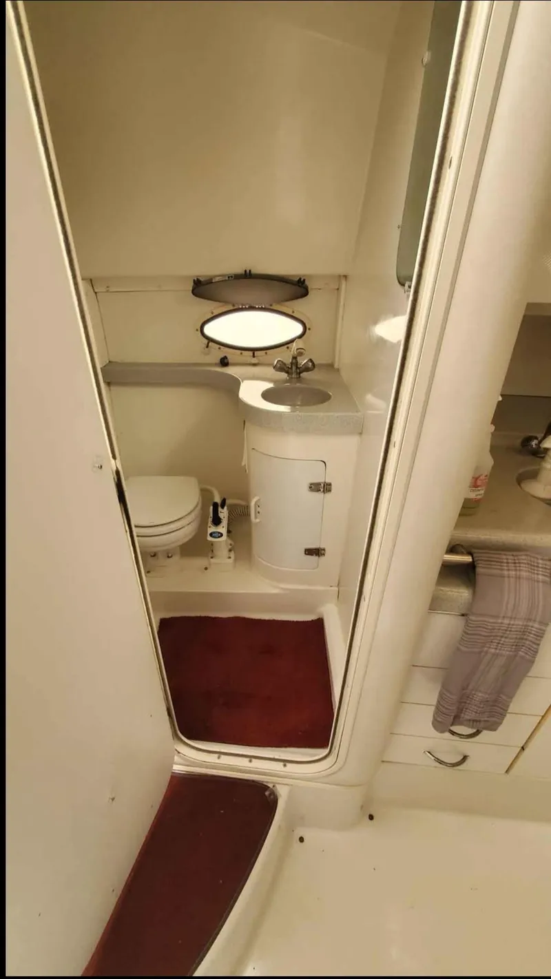 Slide: The Image of Bathroom interior of 1997 Chris-Craft 34 boat, featuring toilet, sink, and porthole window. - 15