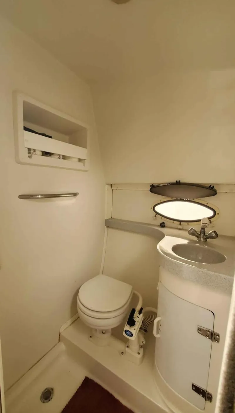 Slide: The Image of 1997 Chris-Craft 34 boat bathroom with toilet, sink, and storage shelf. - 16