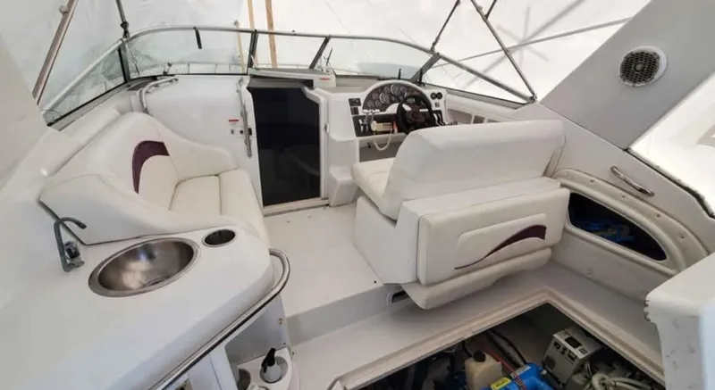 Slide: The Image of 1997 Chris-Craft 34 boat interior with white seating, steering wheel, and sink. - 3