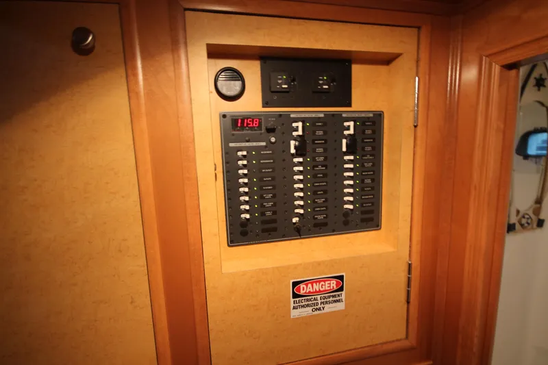 Slide: The Image of Electrical panel on 2011 Gibson 50 Cabin Yacht, featuring voltage display and warning label. - 33