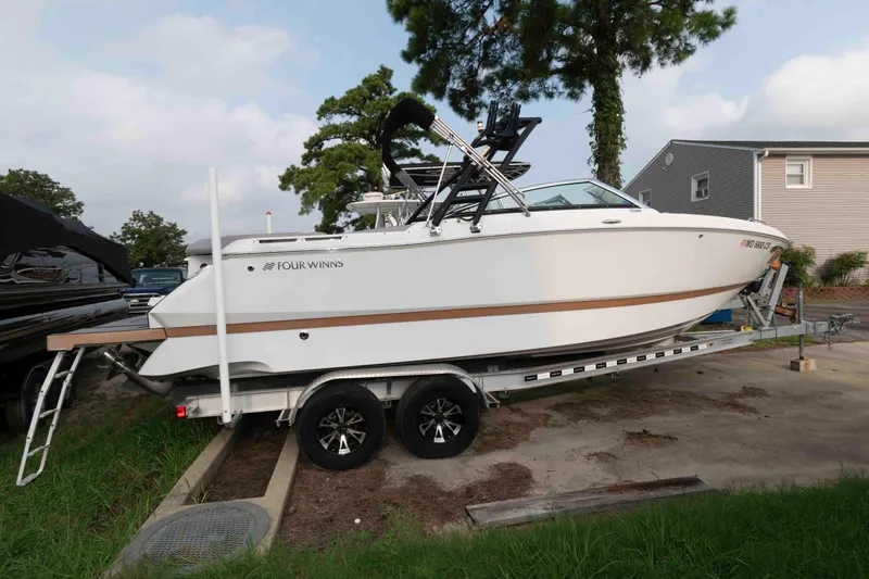 Slide: The Image of 2017 Four Winns H260 boat docked by a wooden pier on a calm lake. - 1