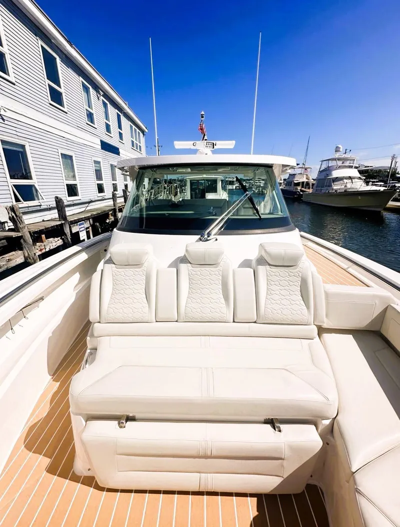 Slide: The Image of 2024 Tiara Yachts 43 LS luxury boat with plush seating, docked near waterfront buildings. - 17