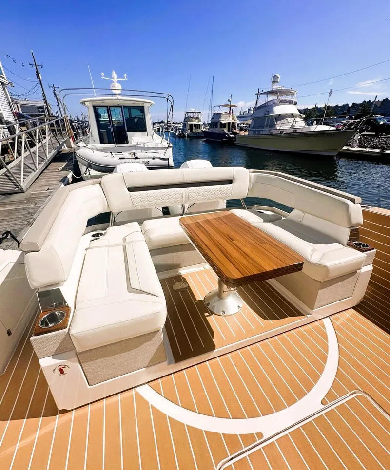 Slide: The Image of 2024 Tiara Yachts 43 LS with elegant seating and wooden table at a marina. - 8