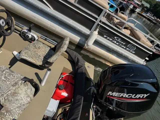 Slide: The Image of 2024 Tracker Grizzly 1648 SC boat with Mercury engine, docked near Sun Tracker pontoon. - 4