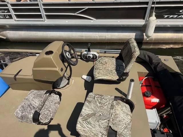Slide: The Image of 2024 Tracker Grizzly 1648 SC boat interior with camo seats and steering console. - 5
