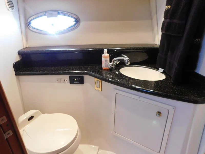 Slide: The Image of 2002 Carver 450 Voyager Pilothouse bathroom with sink, toilet, and porthole window. - 26