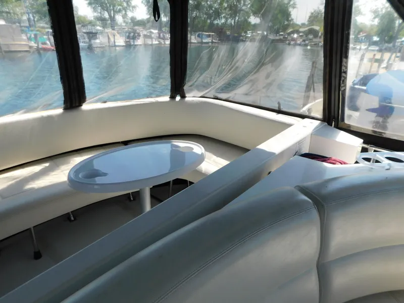 Slide: The Image of Interior of 2002 Carver 450 Voyager Pilothouse with white seating and table, overlooking water. - 29