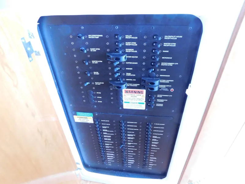 Slide: The Image of Electrical panel of 2002 Carver 450 Voyager Pilothouse with labeled switches and warning signs. - 36