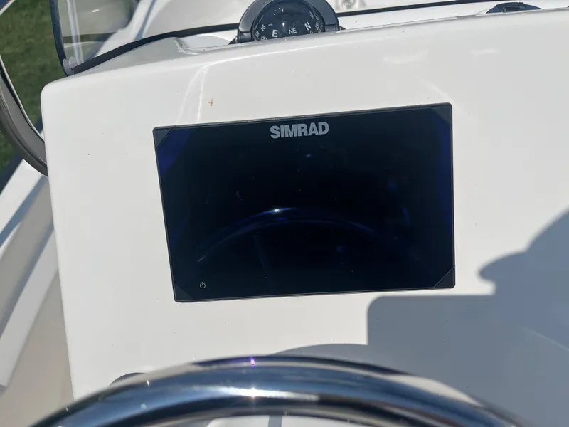 Slide: The Image of 2025 Boston Whaler 150 Montauk dashboard with Simrad display and compass. - 10