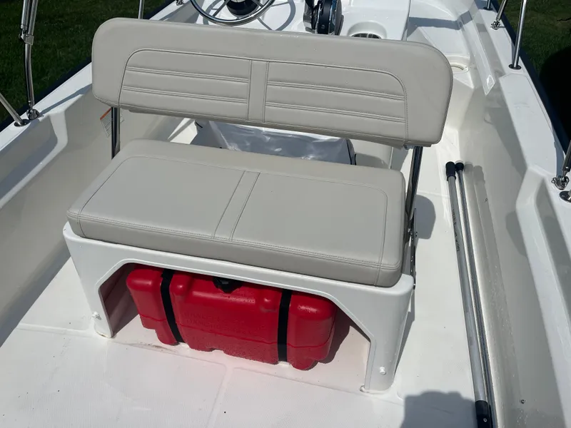 Slide: The Image of 2025 Boston Whaler 150 Montauk boat interior with cushioned seating and storage compartment. - 13