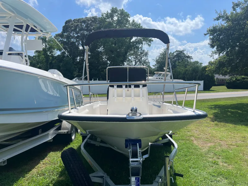 Slide: The Image of 2025 Boston Whaler 150 Montauk boat on trailer, parked on grass under a sunny sky. - 15