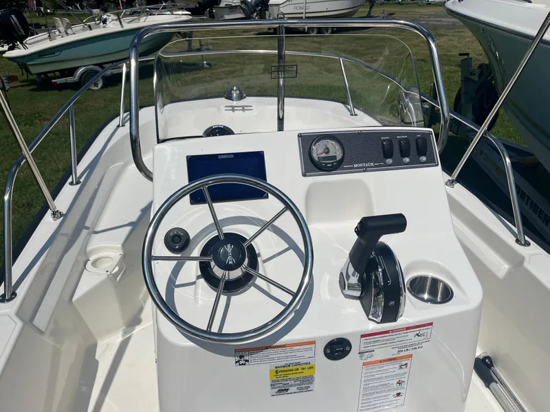 Slide: The Image of 2025 Boston Whaler 150 Montauk boat console with steering wheel and controls. - 5