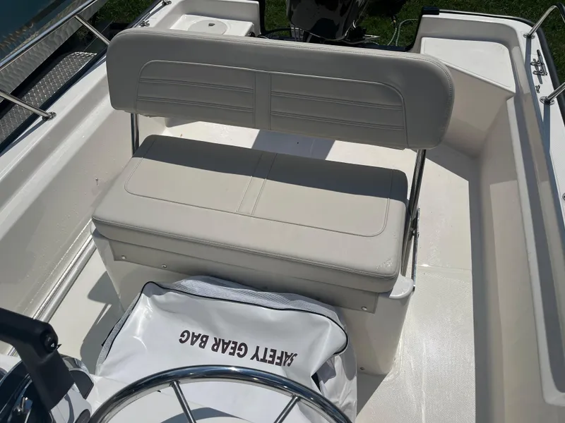 Slide: The Image of 2025 Boston Whaler 150 Montauk boat interior with bench seat and safety gear bag. - 9