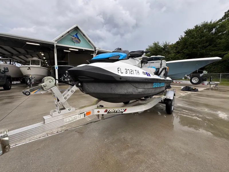 Slide: The Image of 2022 Sea-Doo Fish Pro Scout on trailer, parked near boats under cloudy sky. - 3