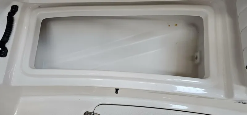 Slide: The Image of 2018 Yamaha Boats 210 FSH Deluxe storage compartment, white interior, open lid. - 12